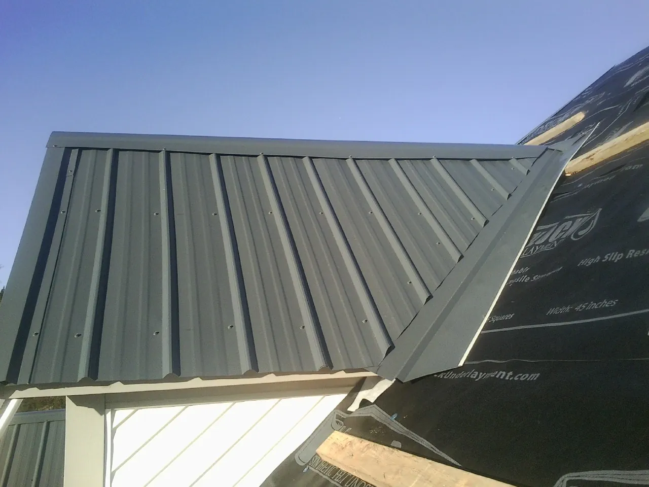 Gray metal roof panels going on over a garage gable in Luther