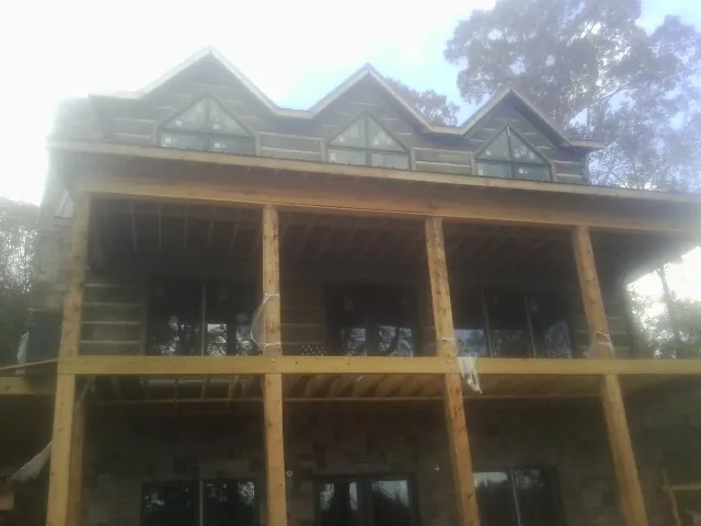 Dormers and porch framing on a large log home under construction — Roof Coating work by our crew in Luther