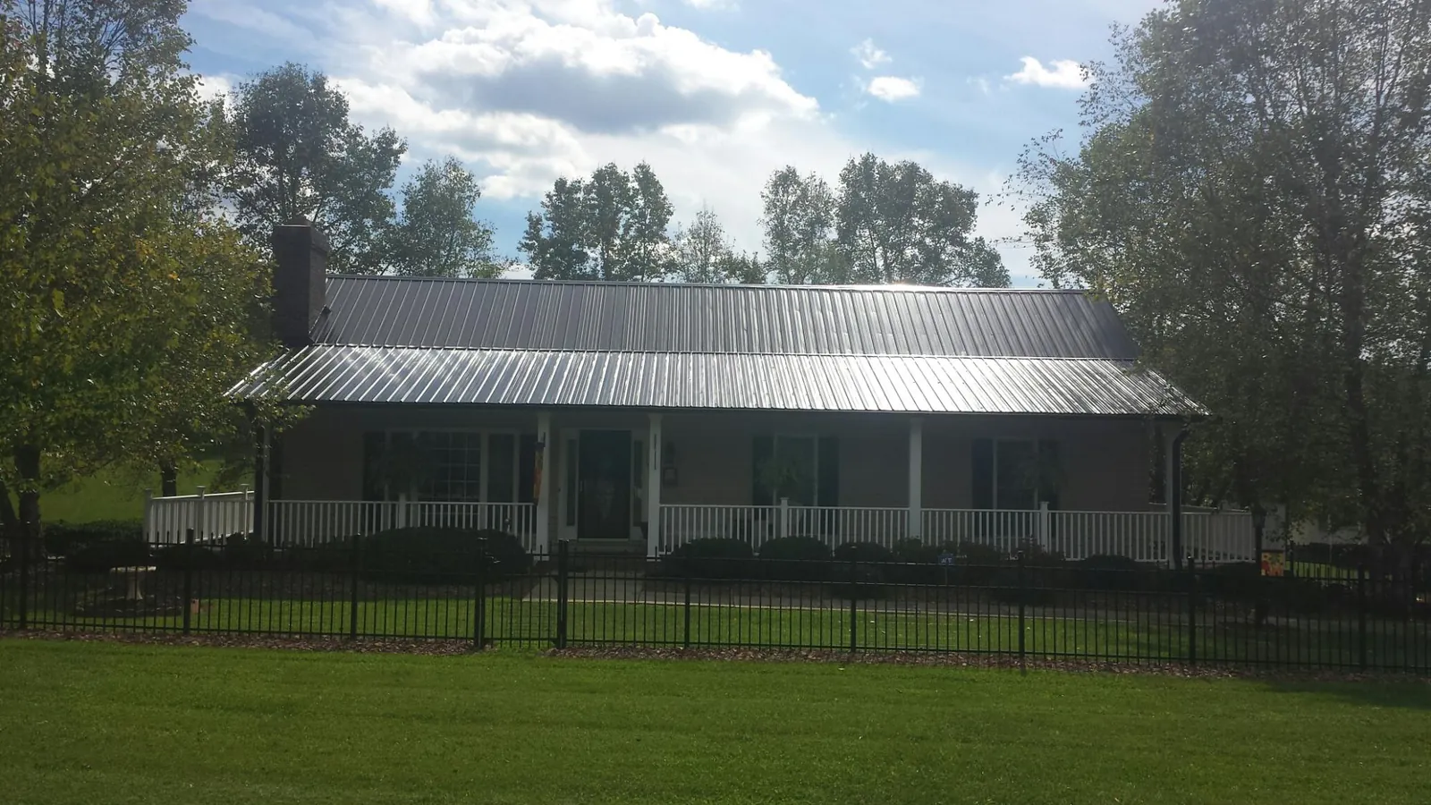 Gray metal roof on a brick ranch with a full width front porch — Gutter Guard Installation work by our crew in Luther