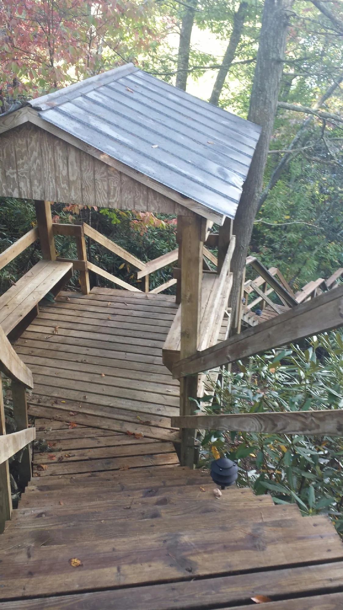Metal roofed shelter over wooden steps on a wooded walkway — Skylight Repair & Installation work by our crew in Luther